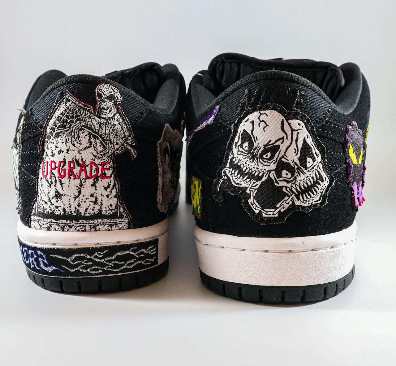 Black sneakers featuring artistic skull designs and vibrant embroidery details.